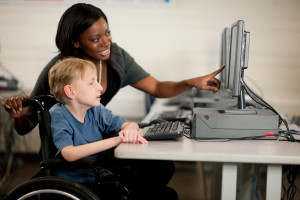 A boy in a wheelchair at the computer.